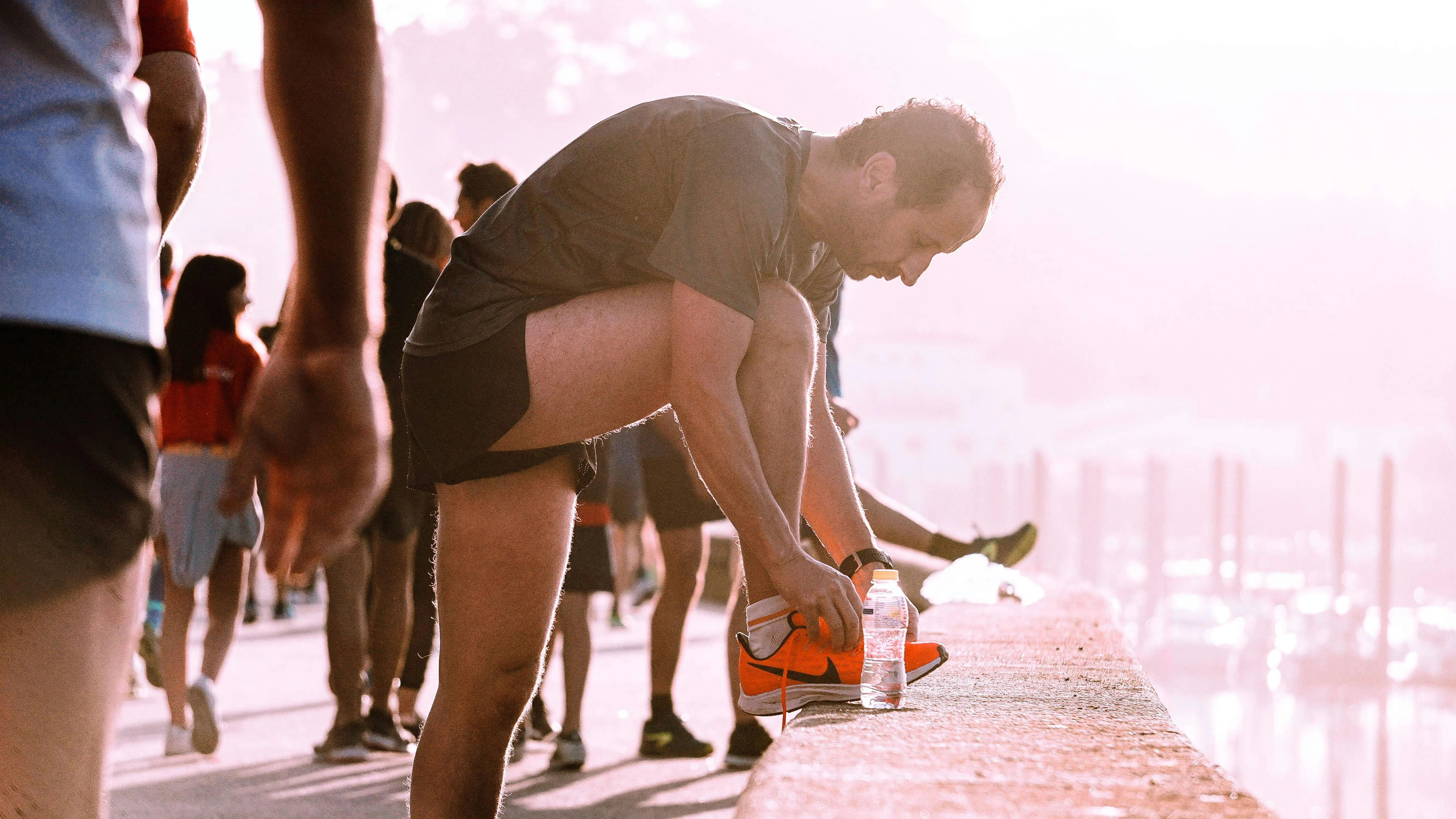 Runner tying a shoe at sunset, back to activity after foot treatment